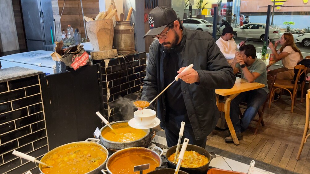 Homem servindo caldos em caldeirões