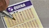 Uma mão segura uma caneta e prencheendo um volante da Quina