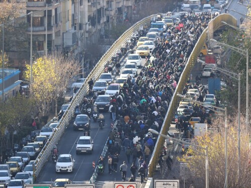 Lojistas e comerciantes atravessam uma ponte durante um protesto contra a situação econômica e a desvalorização da moeda iraniana em Teerã, em 29 de dezembro de 2025.
