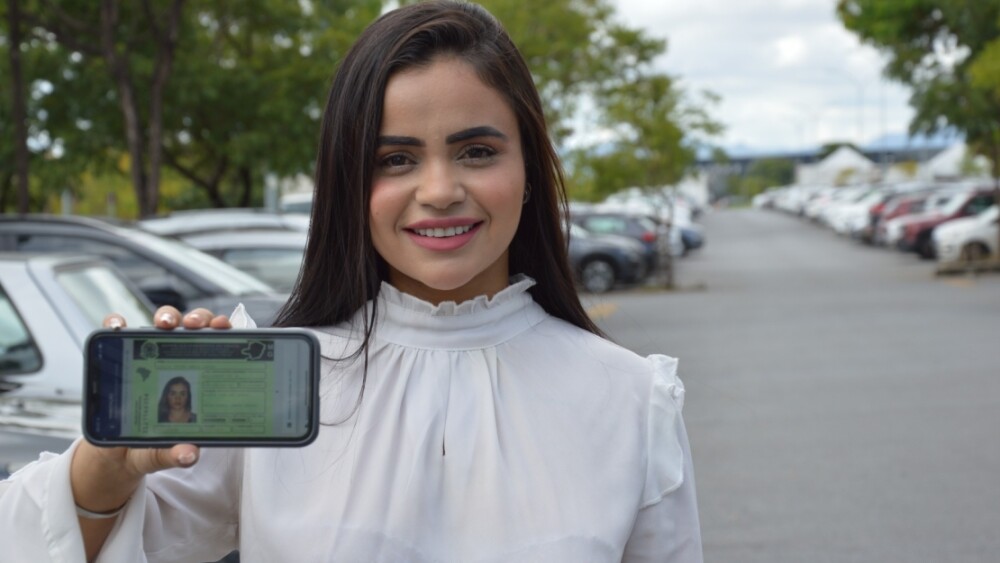 Mulher segura celular com carteira de motorista