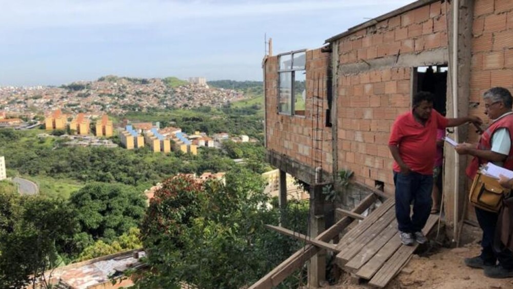 Foto mostra agente da Prefeitura de Belo Horizonte conversando com morador de área de risco