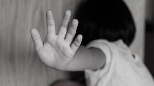 Criança tampa o rosto com a palma da mão