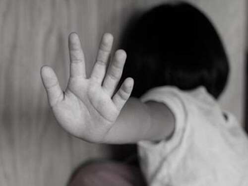 Criança tampa o rosto com a palma da mão